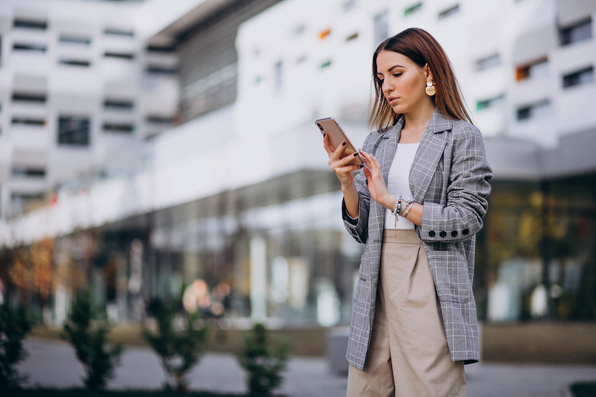Businesswoman checking her phone outside an office building